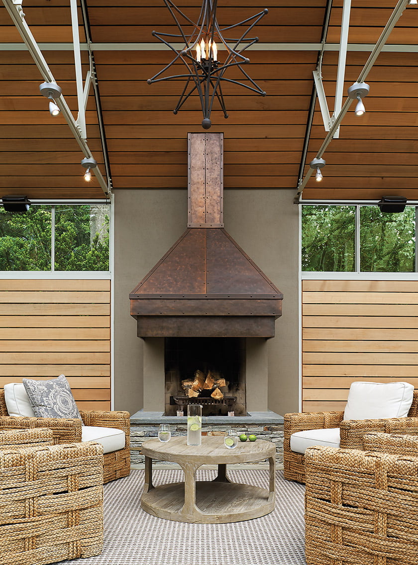 The front entry aligns with the fireplace, made of stucco with a burnished-copper hood and a stacked-stone hearth.