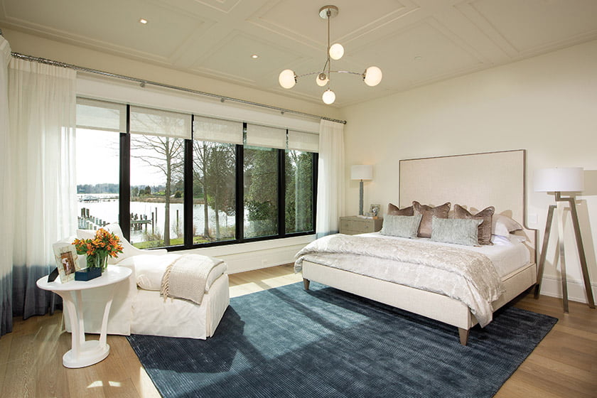 Water views inspired the blue Jaipur rug In the owners’ suite, which contrasts with the white-on-white furnishings.