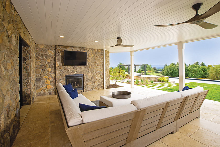 Lower level covered porch bordered by stone foundation walls
