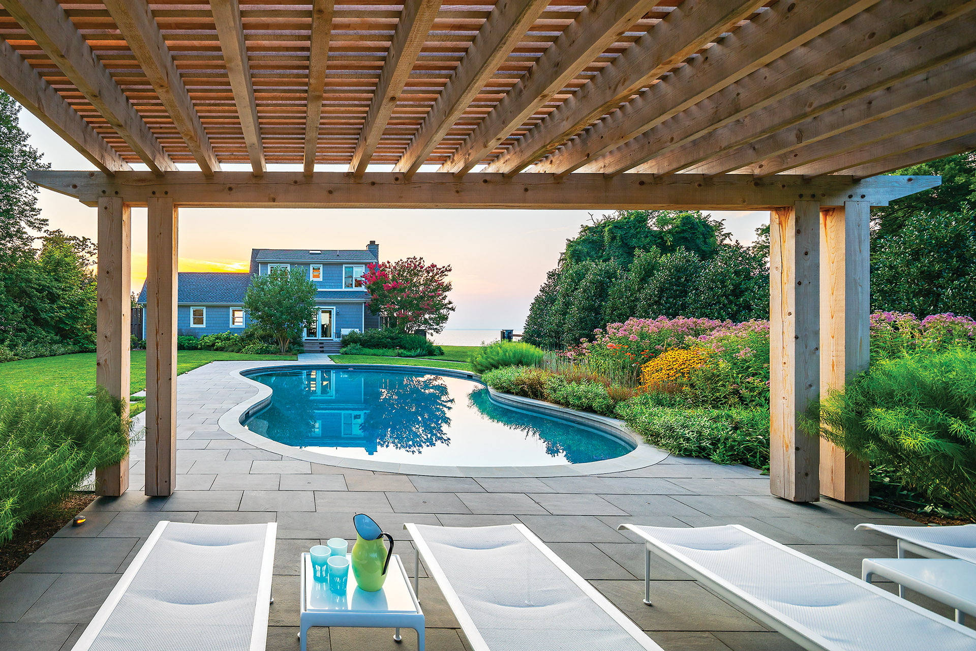 Pergola lounge area by pool, house and bay.