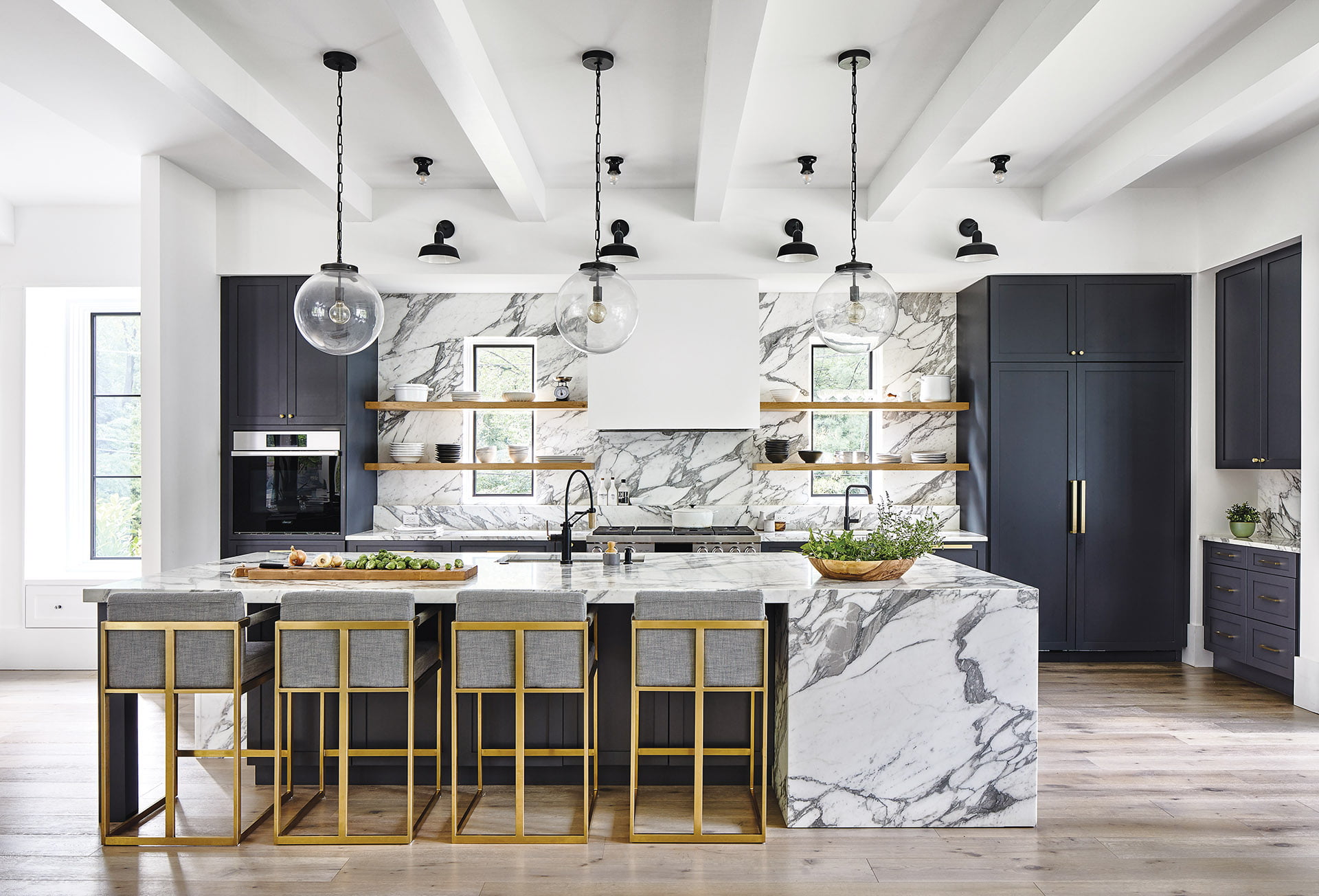 Calacatta Vagli marble surfaces with globe pendants above the island.