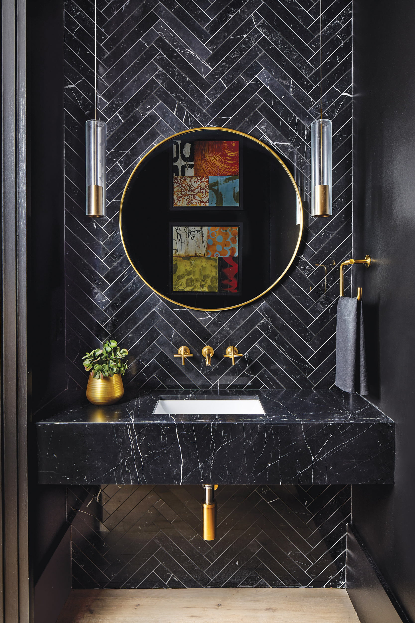 Powder room offsets Nero Marquina marble surfaces with gold accents and RH pendants.