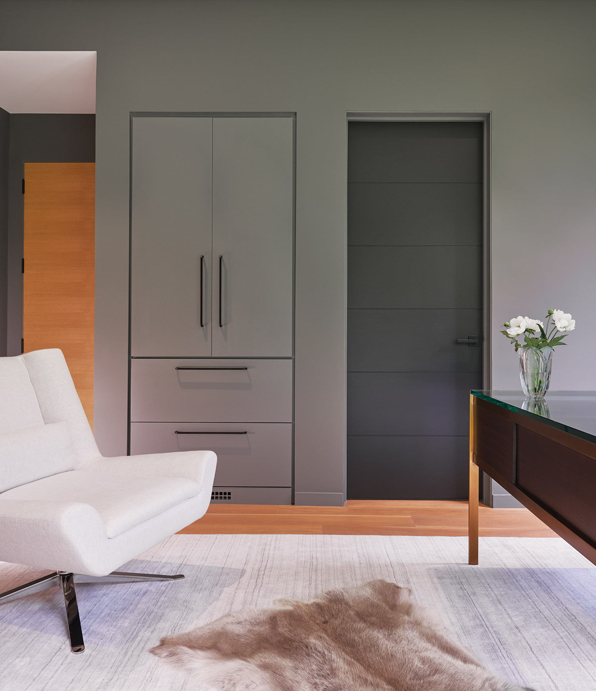 Office with built-in storage cabinets and drawers blend seamlessly into the moody, gray-painted walls.
