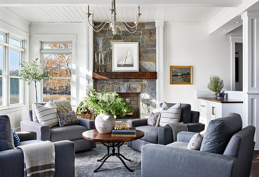 Earthy palette of pale gray, wood and natural stone in the sunroom  with rustic beam on mantel.