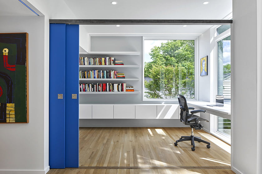 Office with built-ins and shelving by New Era Builders. A sliding door designed by KUBE is spray-painted in Sherwin-Williams’ Adriatic Sea.