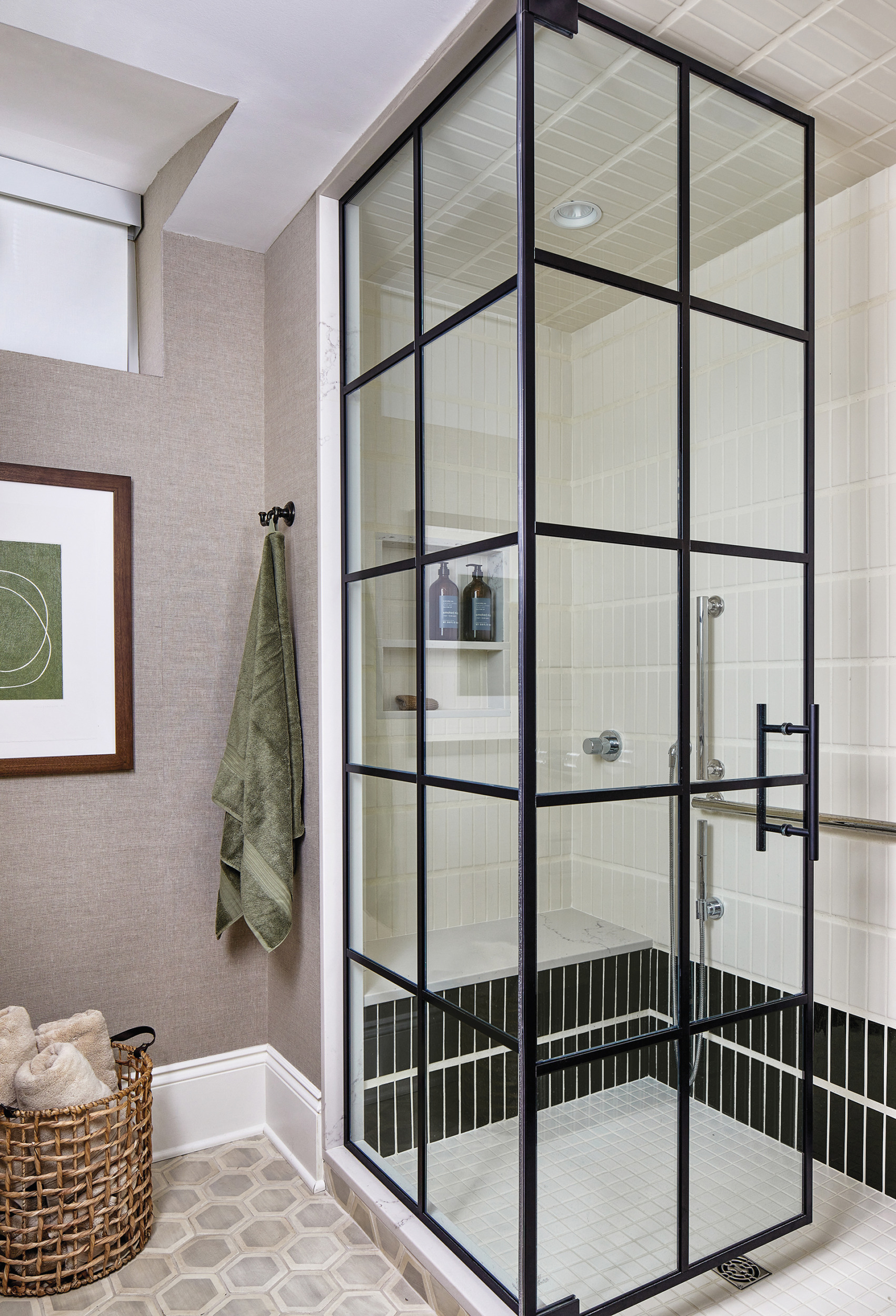 Lower level ensuite bath with matte-white shower tiles bordered by glossy dark-green tiles and hexagon floor tile | Home and Design