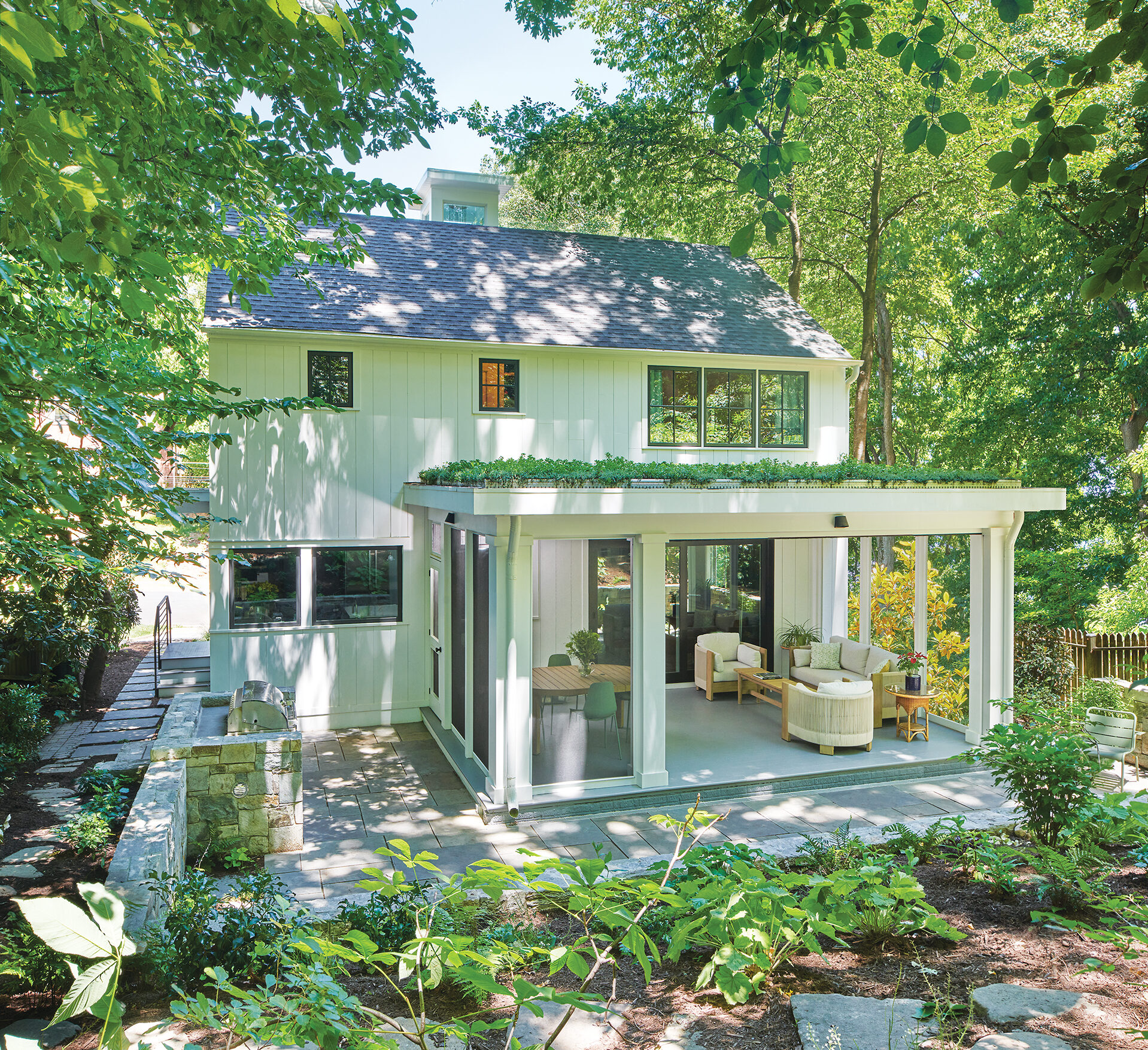 Screened porch with a flat green roof on a white-brick Colonial home