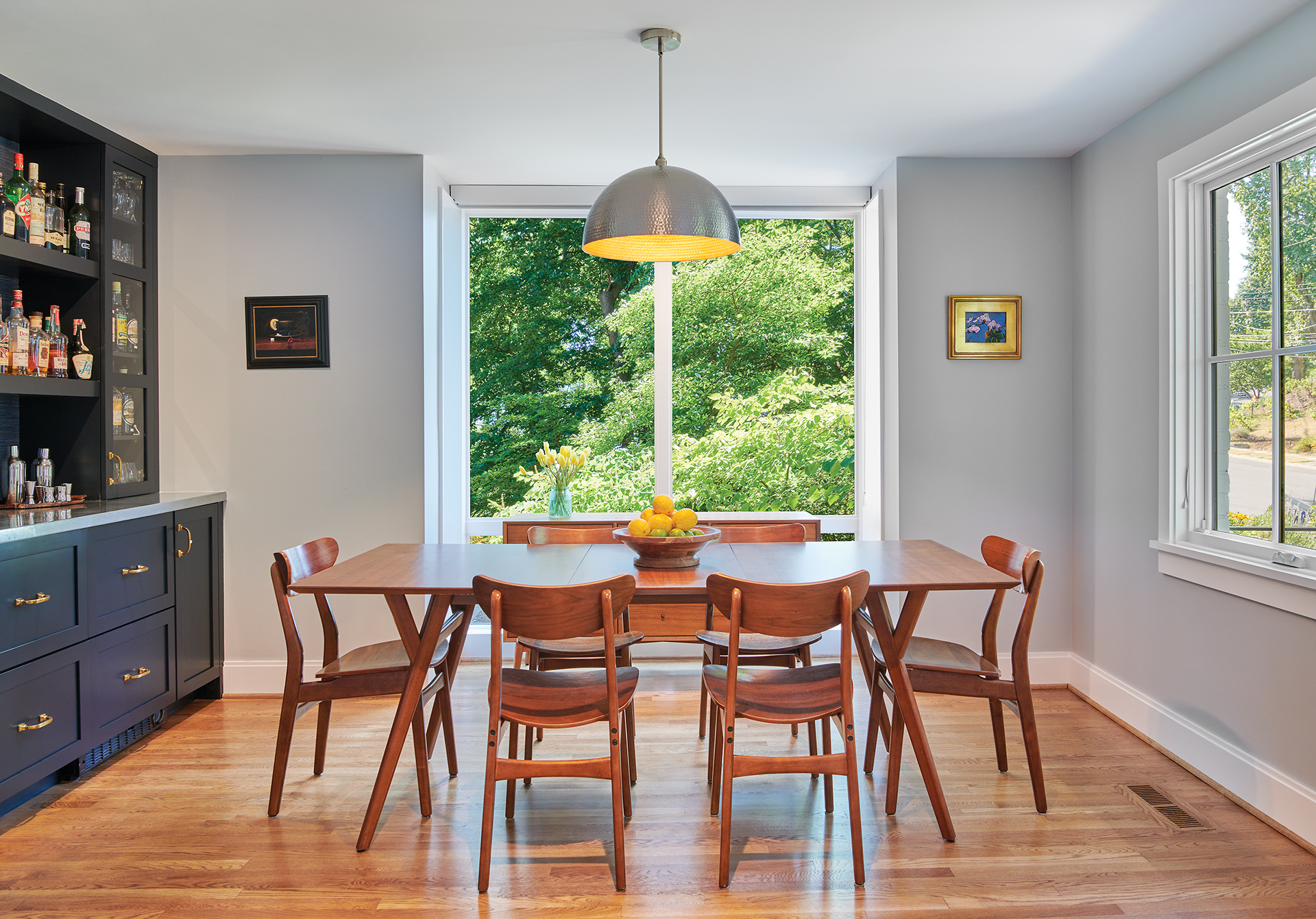 modern dining room with large windows and a minimalist dining table and chairs and blue built-ins for a bar.